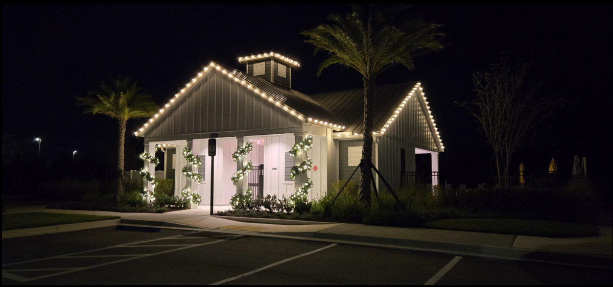Professional seasonal Christmas light installation and holiday lighting rental on a clubhouse with roofline lights and wreath decorations in The Villages, FL