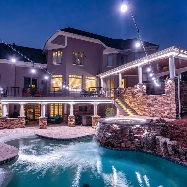 Bright white LED lighting illuminating a pool, patio, and outdoor living area at night