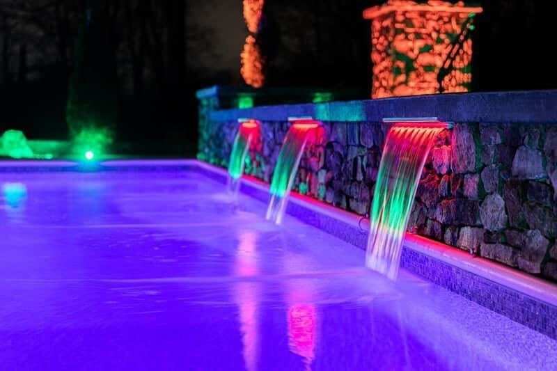 Color-changing LED lighting on pool water features with illuminated waterfalls