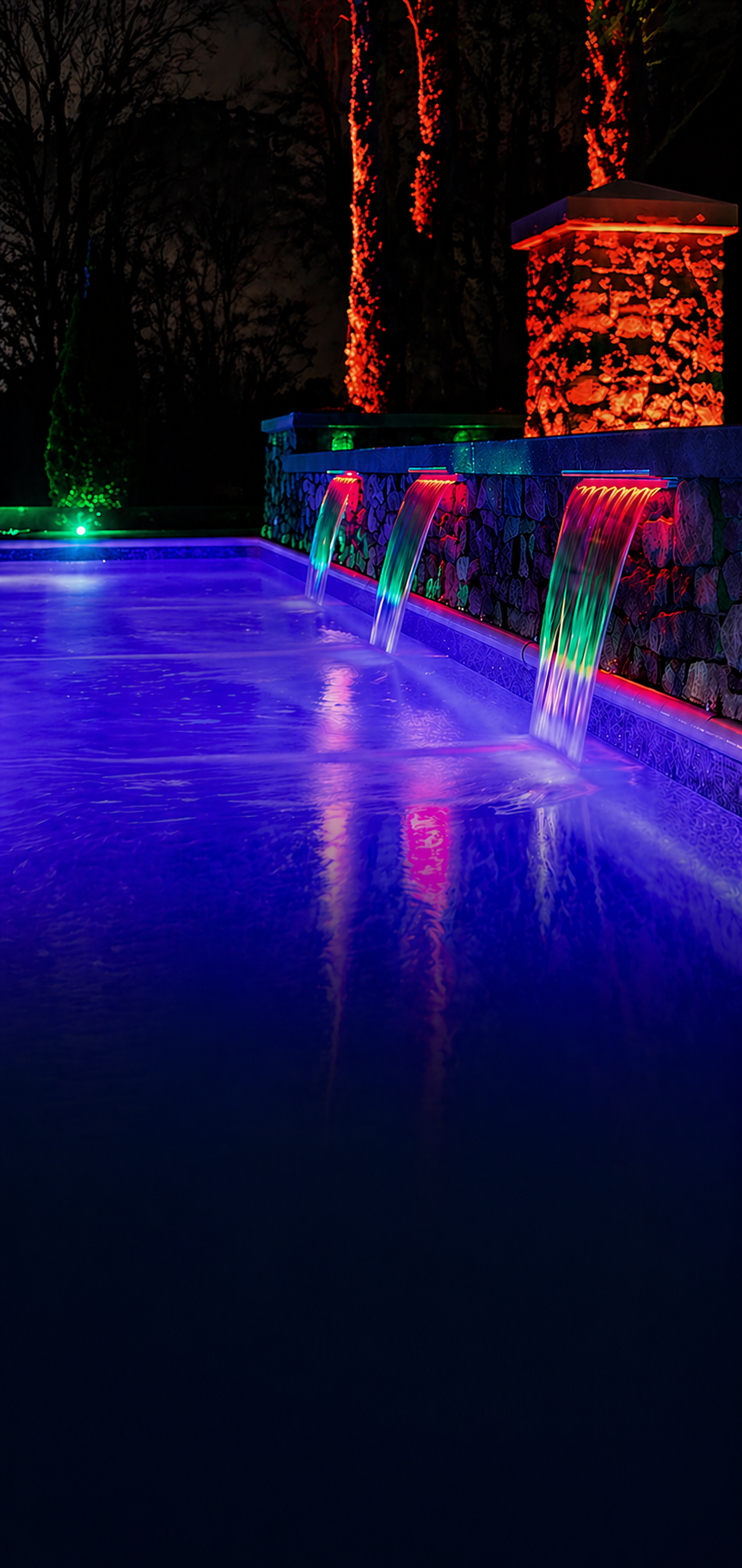 Custom outdoor lighting system with color-changing LED pool and waterfall lighting designed for backyard ambiance and nighttime enjoyment in The Villages FL