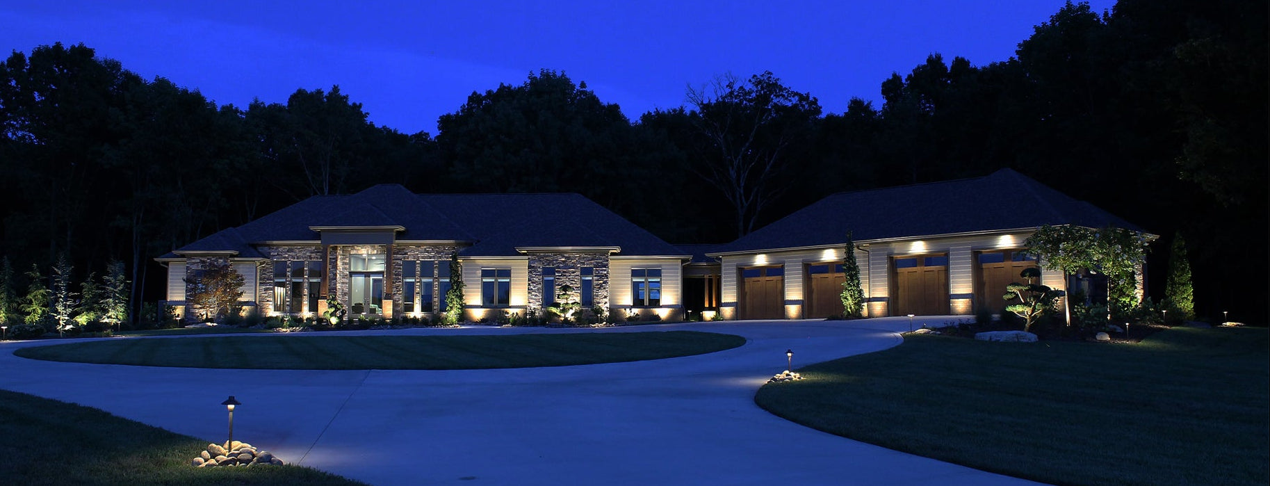 professional landscape lighting installation illuminating large estate home and driveway