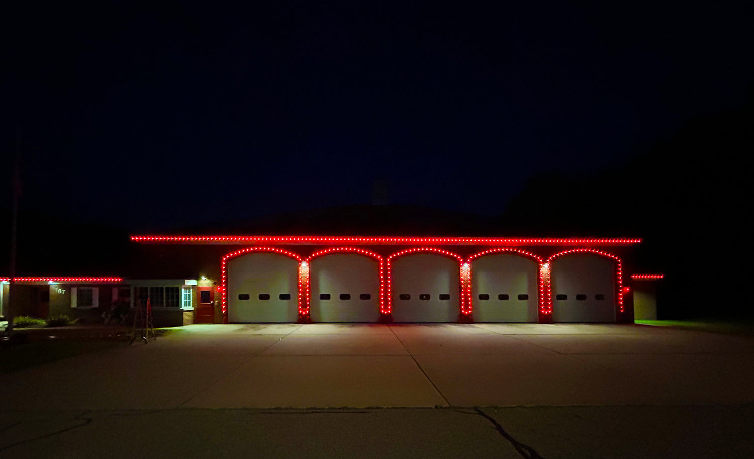 Commercial roofline lighting installed on a fire station with bright red LED lighting outlining the roofline and garage bays.