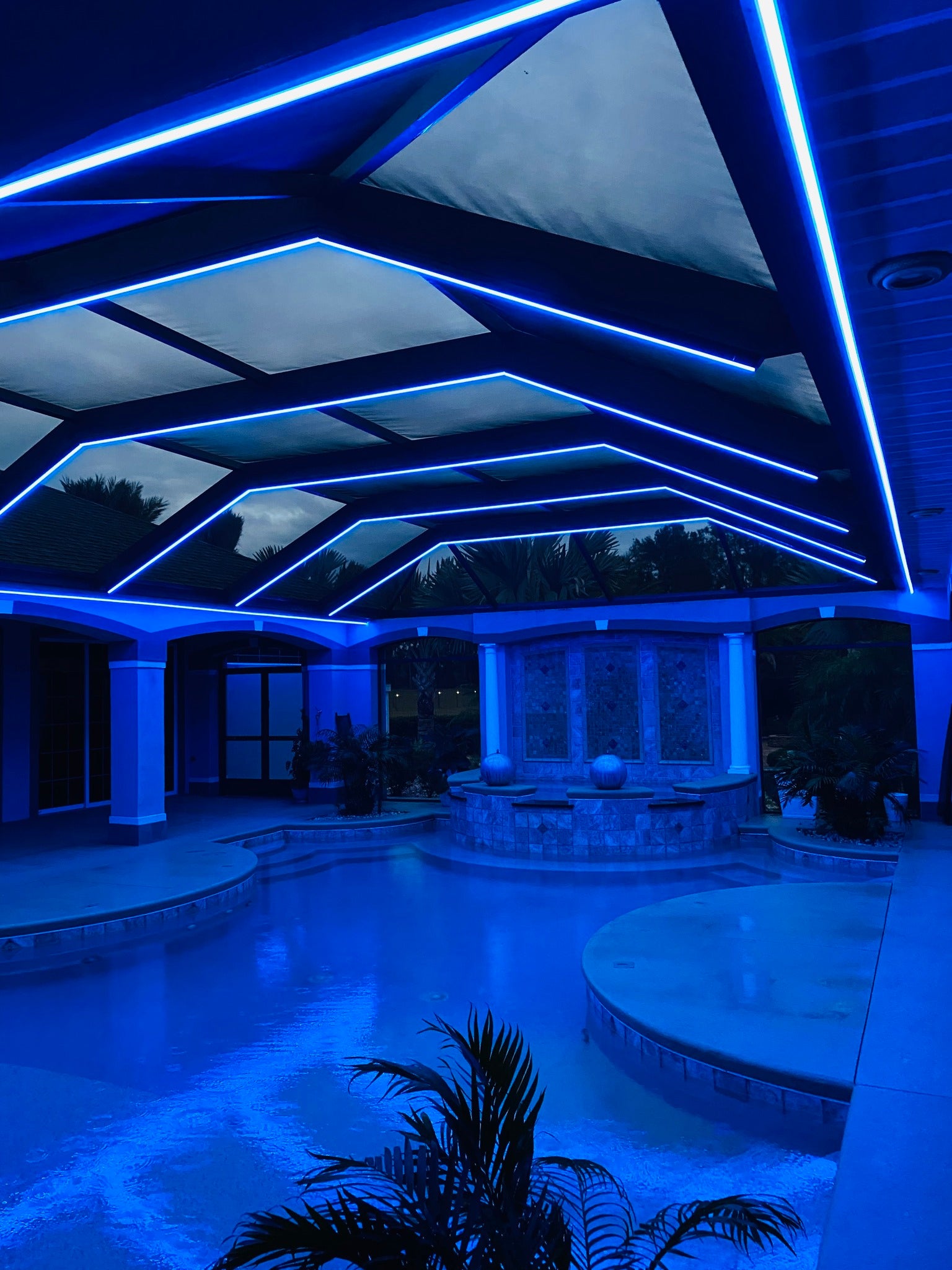 Blue LED lighting installed along a screened lanai cage structure creating dramatic nighttime pool lighting