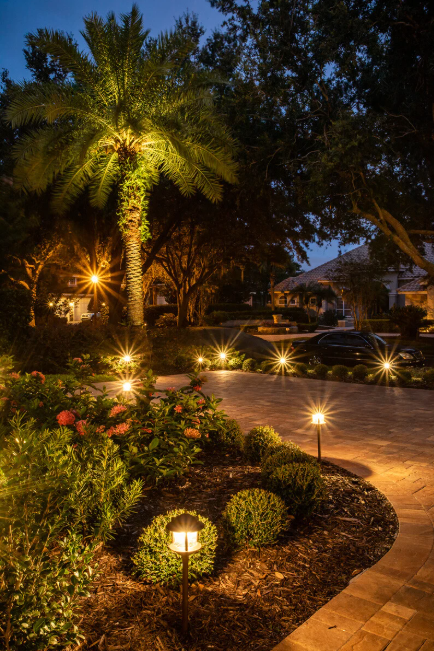 Landscape and pathway lighting illuminating residential paver walkway and garden beds in The Villages Florida