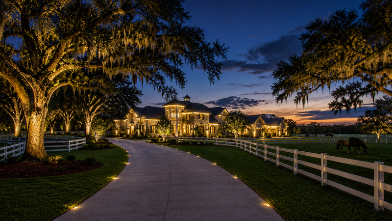Custom outdoor lighting design in Ocala Florida featuring large home with column lighting, roofline lighting, and landscape lighting throughout the property