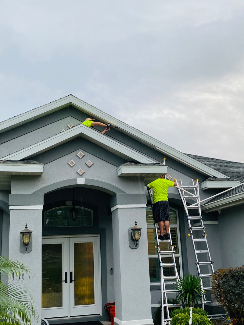 Technicians installing permanent roofline lighting on a home in Florida