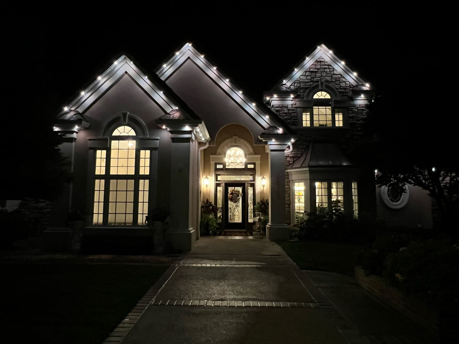 Permanent roofline lighting outlining residential home architecture with warm white LED lighting