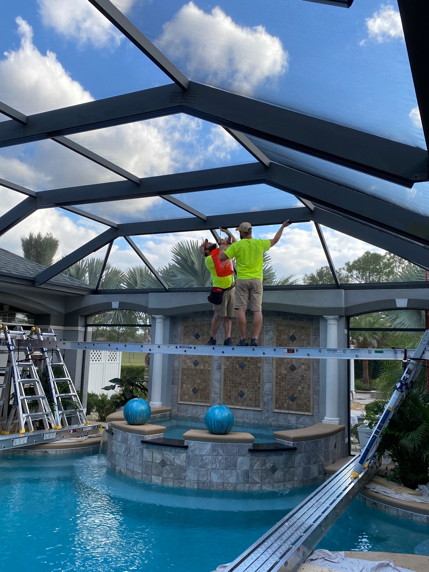 Light Glow team installing outdoor lighting on a pool cage structure in Florida